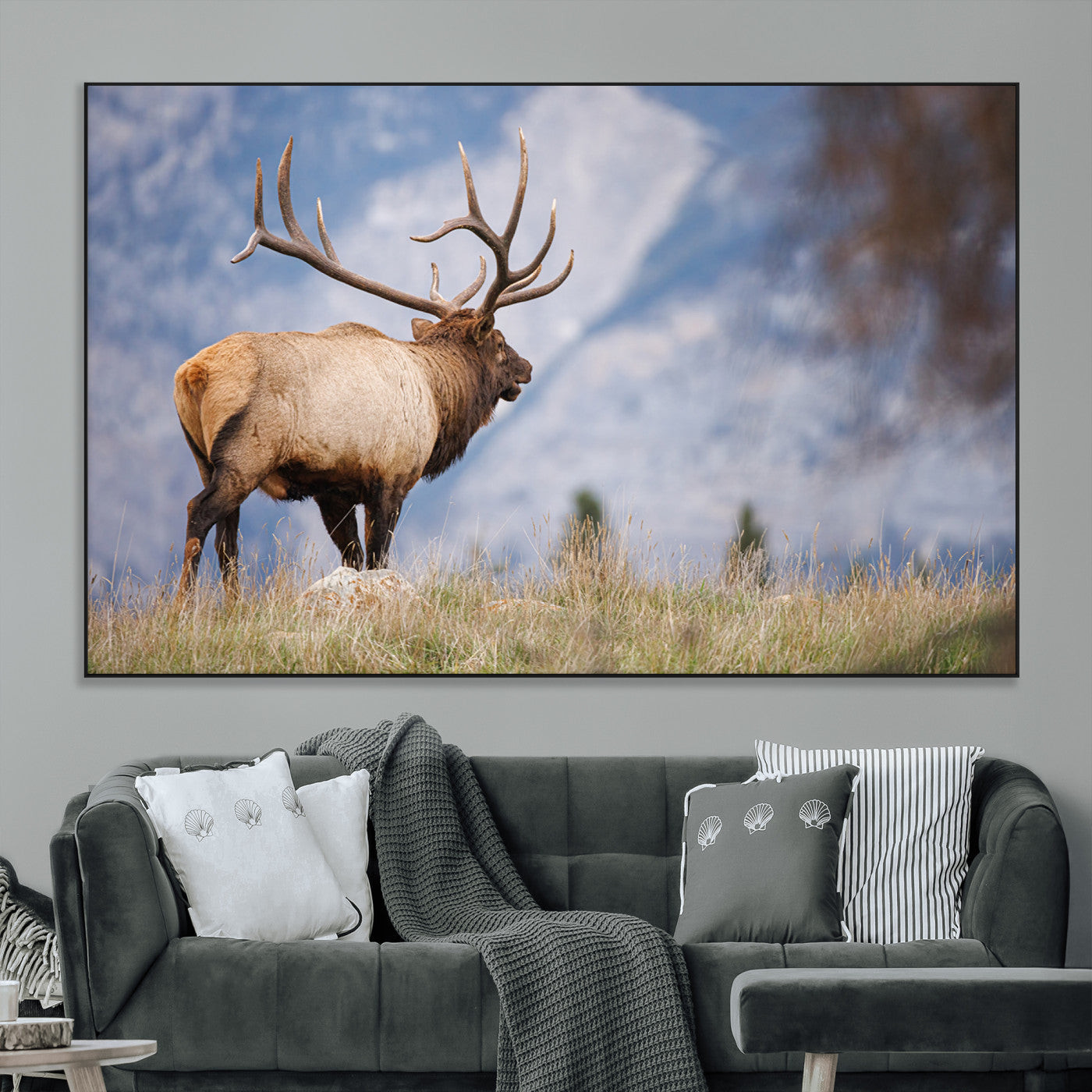Elk with antlers standing on grass with mountain background, ideal for rustic, cabin, or lodge-inspired wall decor.