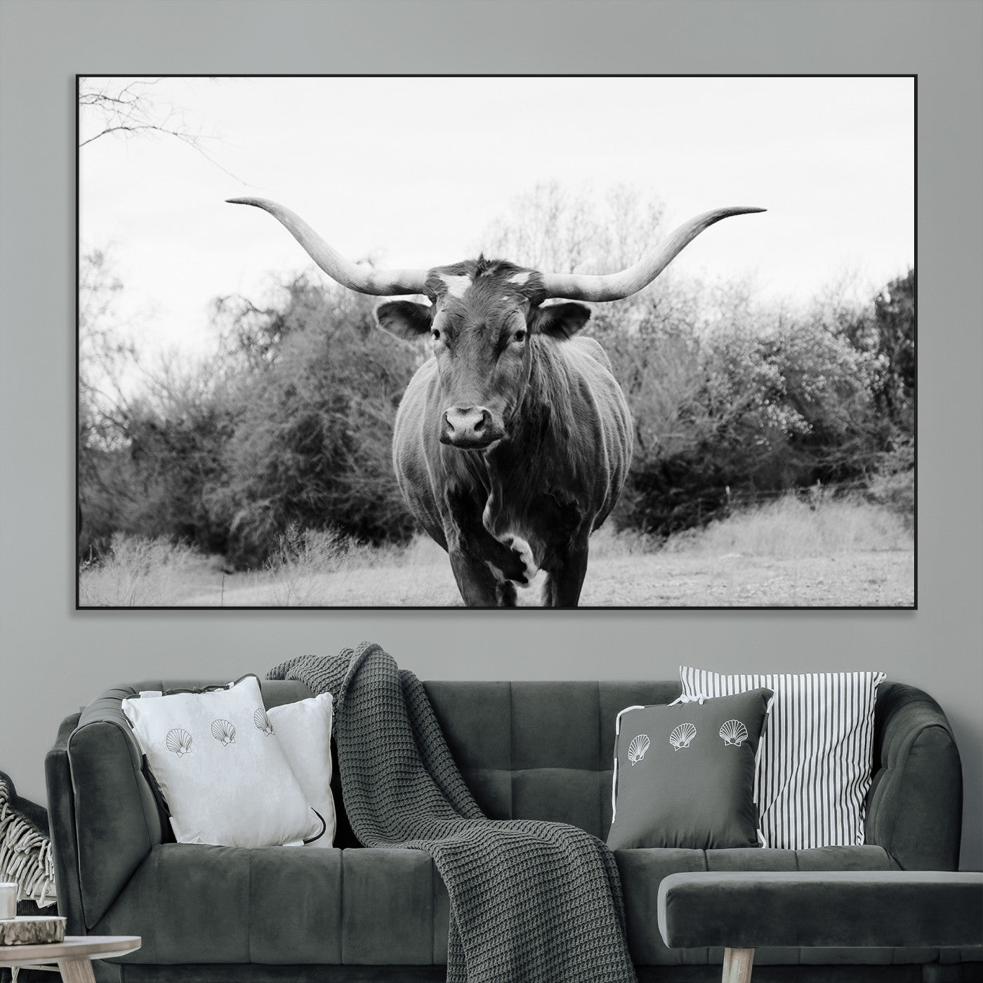 Black and white photo of a longhorn cow in a field, perfect for rustic farmhouse or western-themed interior wall decoration.
