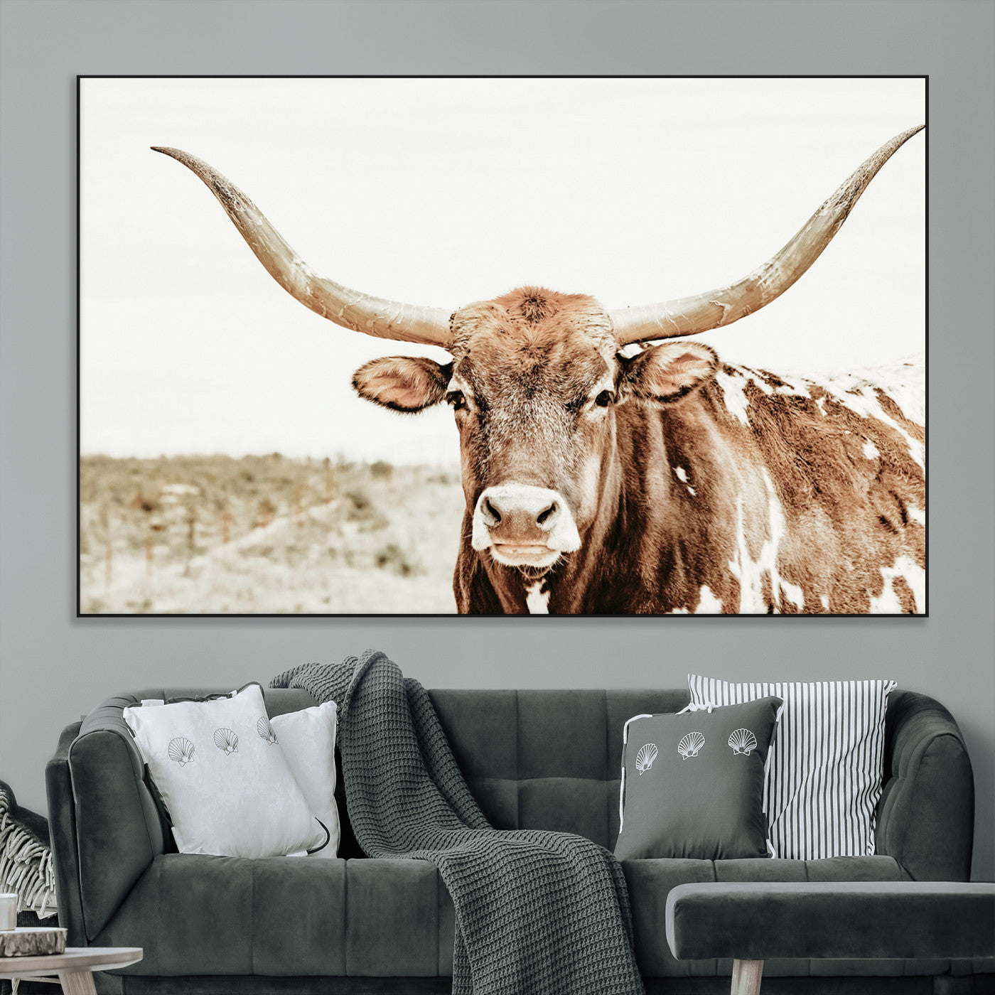 A Texas longhorn bull with wide horns, standing in a dry field under soft light, ideal for rustic farmhouse or western-themed interiors.