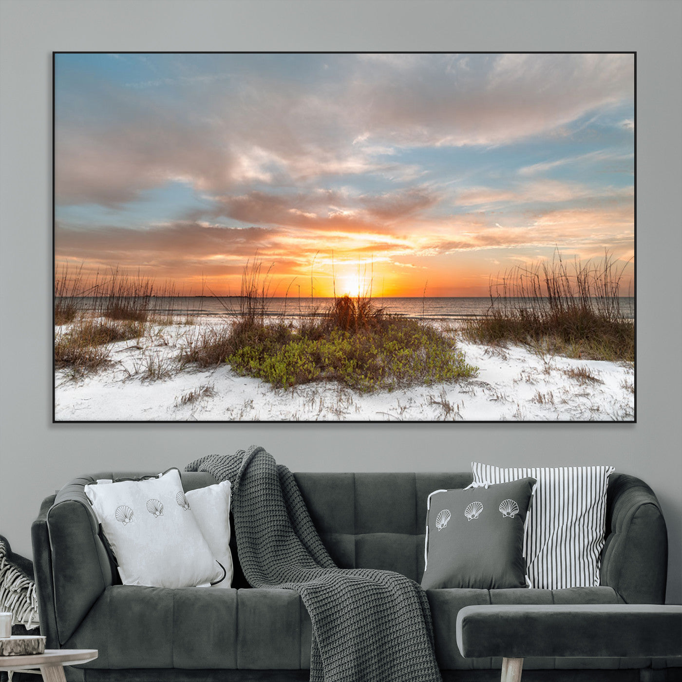 A tranquil beach scene featuring golden sunset hues over the water, with grasses in the foreground and a peaceful, serene atmosphere.