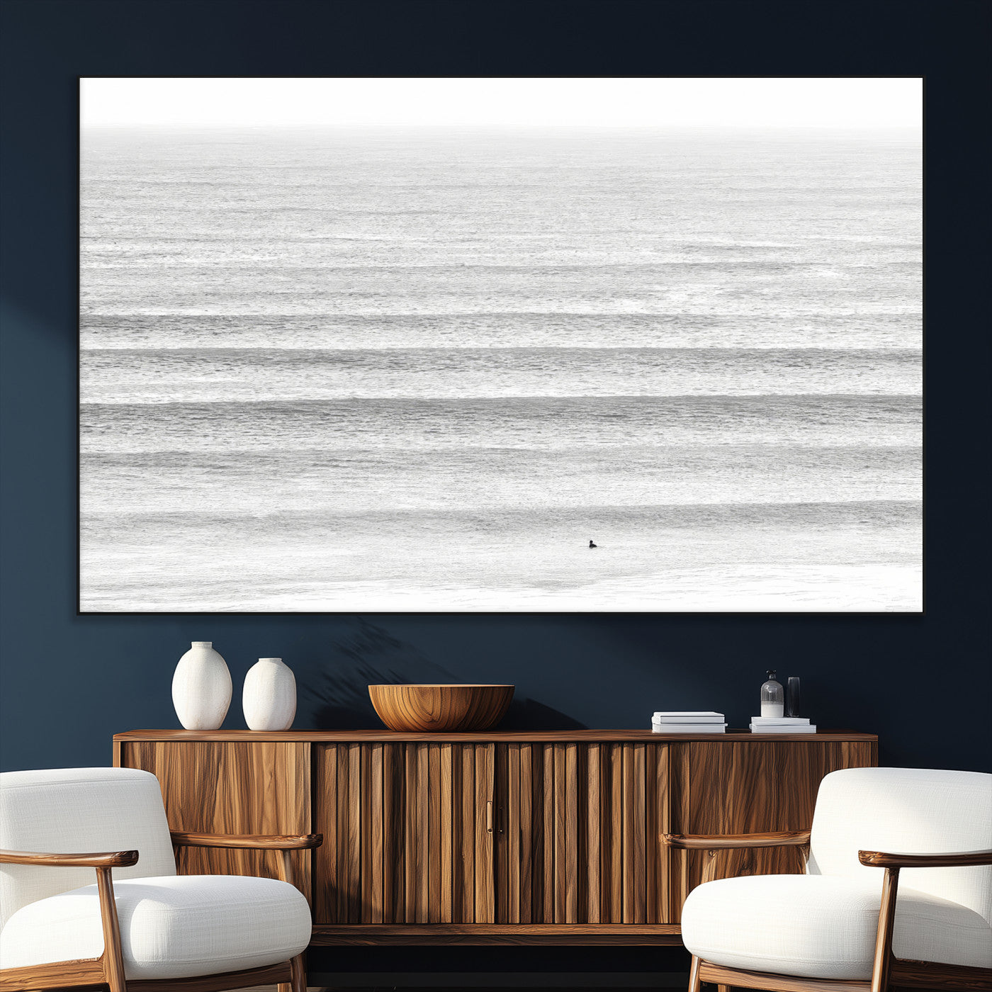 Monochrome photo of a lone surfer in calm layered waves, perfect for minimalist coastal or moody ocean-inspired wall decoration.
