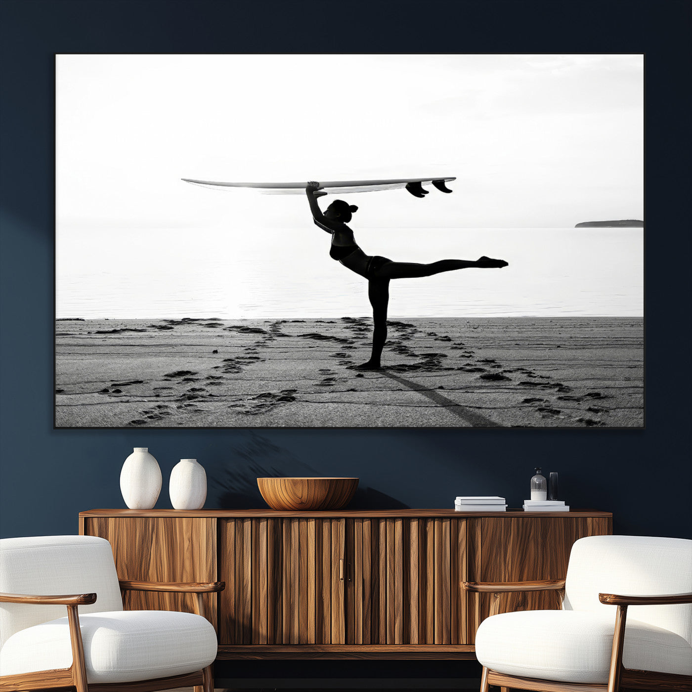 A woman balances a surfboard on her head while striking a yoga pose on the beach, silhouetted against a calm ocean horizon.