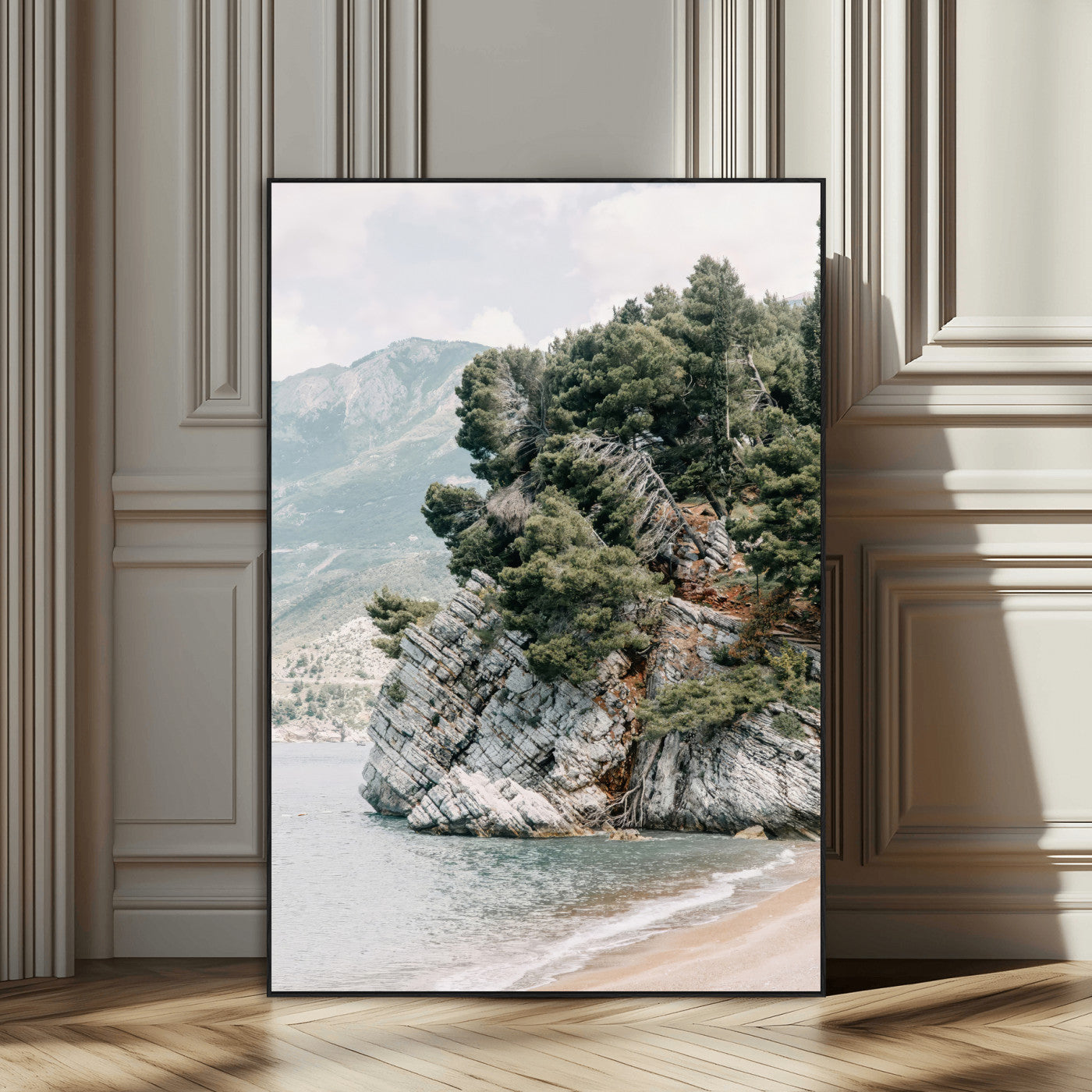 Framed photo of a rocky coastal cliff with dense greenery and calm shoreline, ideal for rustic coastal or earthy-toned home decor.