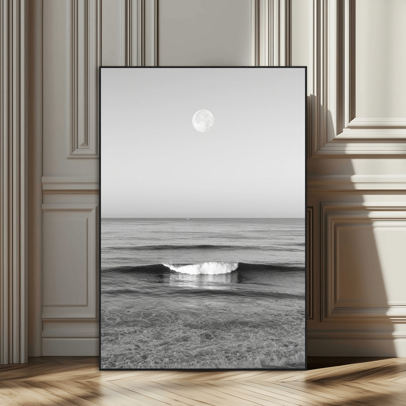 Black and white wall art of a calm ocean wave beneath a full moon, ideal for minimalist or monochrome coastal decor.