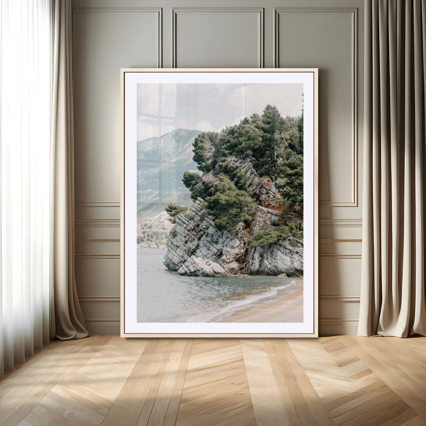Framed photo of a rocky coastal cliff with dense greenery and calm shoreline, ideal for rustic coastal or earthy-toned home decor.