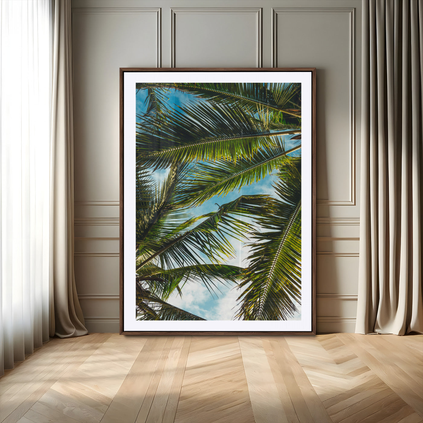 Looking up at lush green palm leaves against a bright blue sky, creating a tropical and relaxing coastal aesthetic.