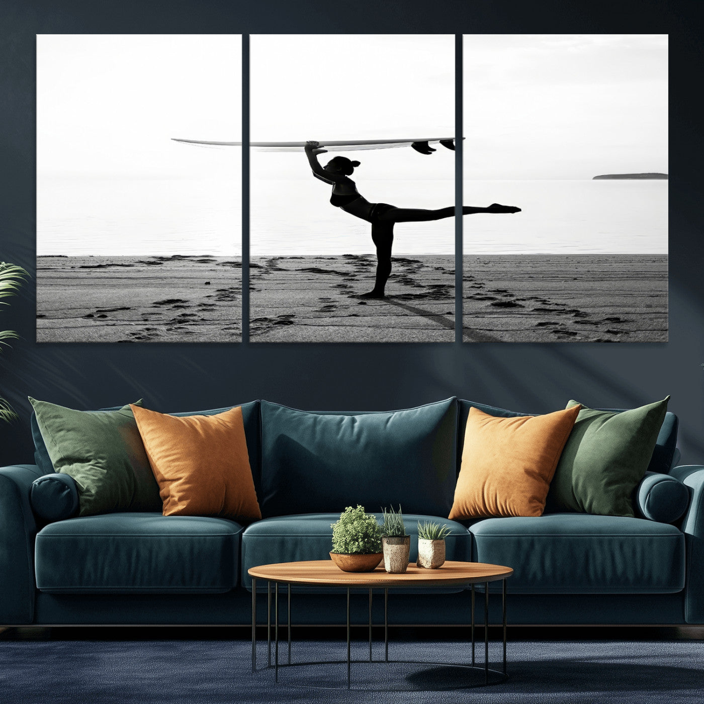 A woman balances a surfboard on her head while striking a yoga pose on the beach, silhouetted against a calm ocean horizon.