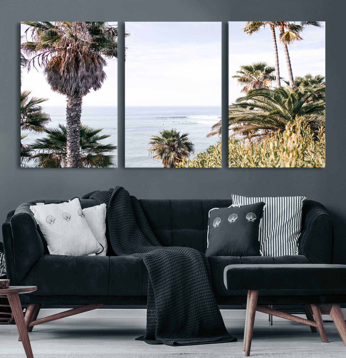 Scenic coastal view with tall palm trees overlooking a calm ocean, soft blue waves, and surfers in the distance, creating a peaceful tropical vibe.
