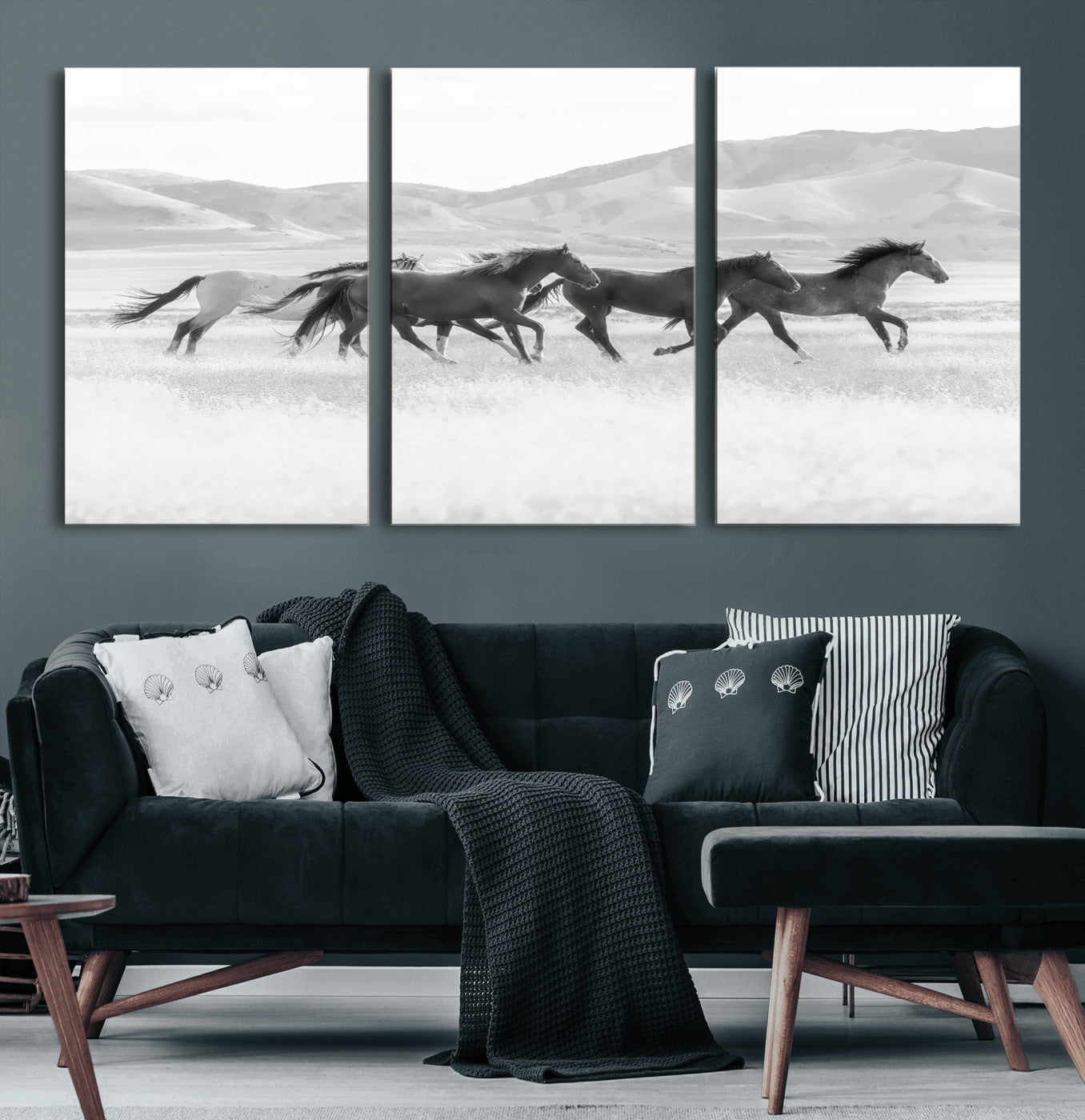 A black and white image of wild horses running freely across an open grassland, capturing the power and beauty of untamed nature in a rustic western setting.