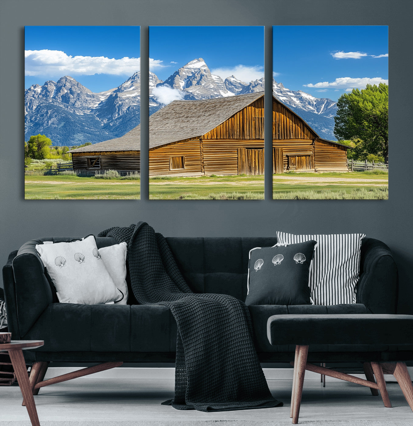 A rustic wooden barn sits in front of towering mountain peaks under a clear blue sky, perfect for farmhouse or cabin style interiors.