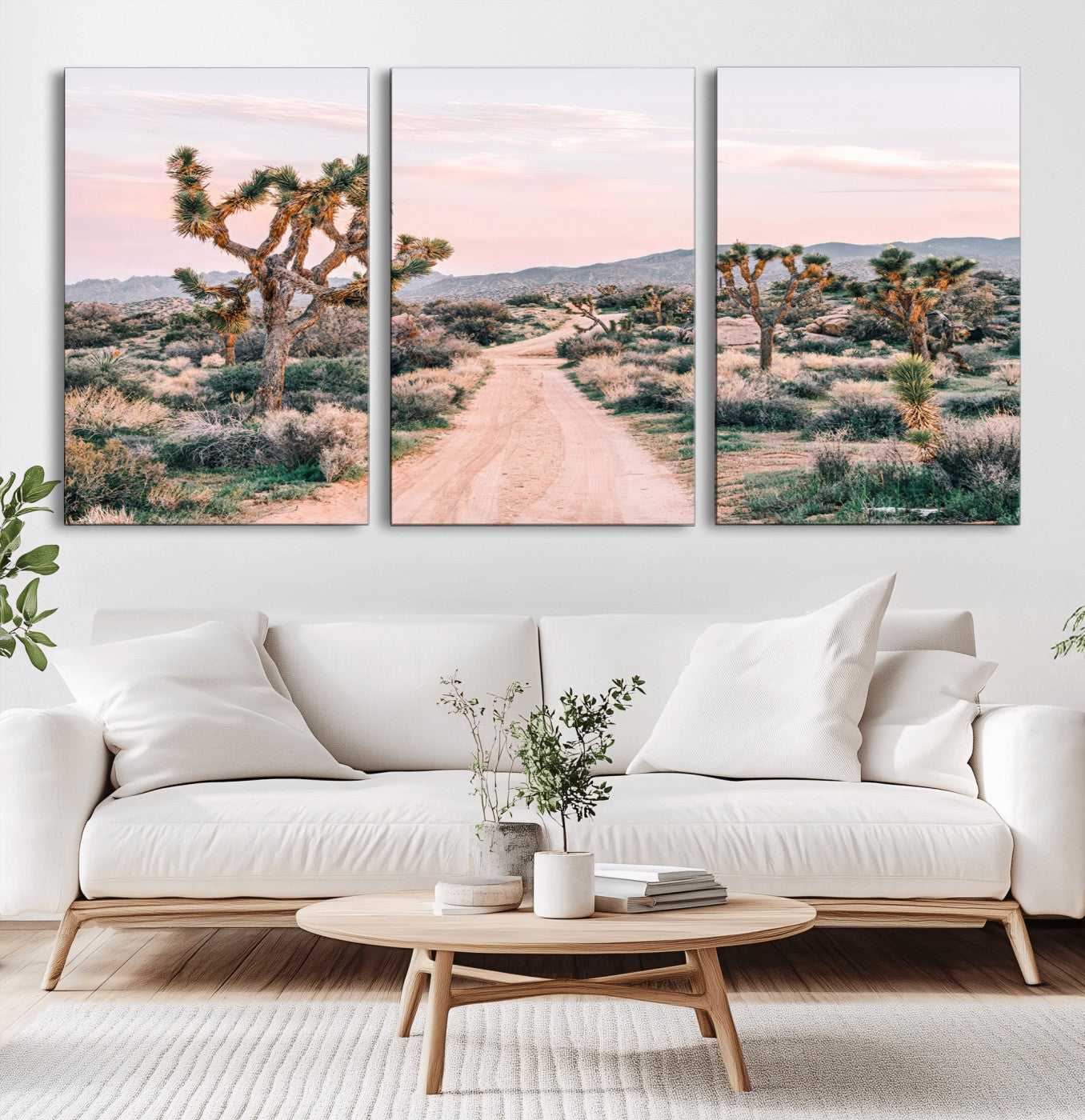 A dusty road winding through Joshua Tree National Park, framed by iconic twisted trees and warm desert tones under a soft pastel sky.