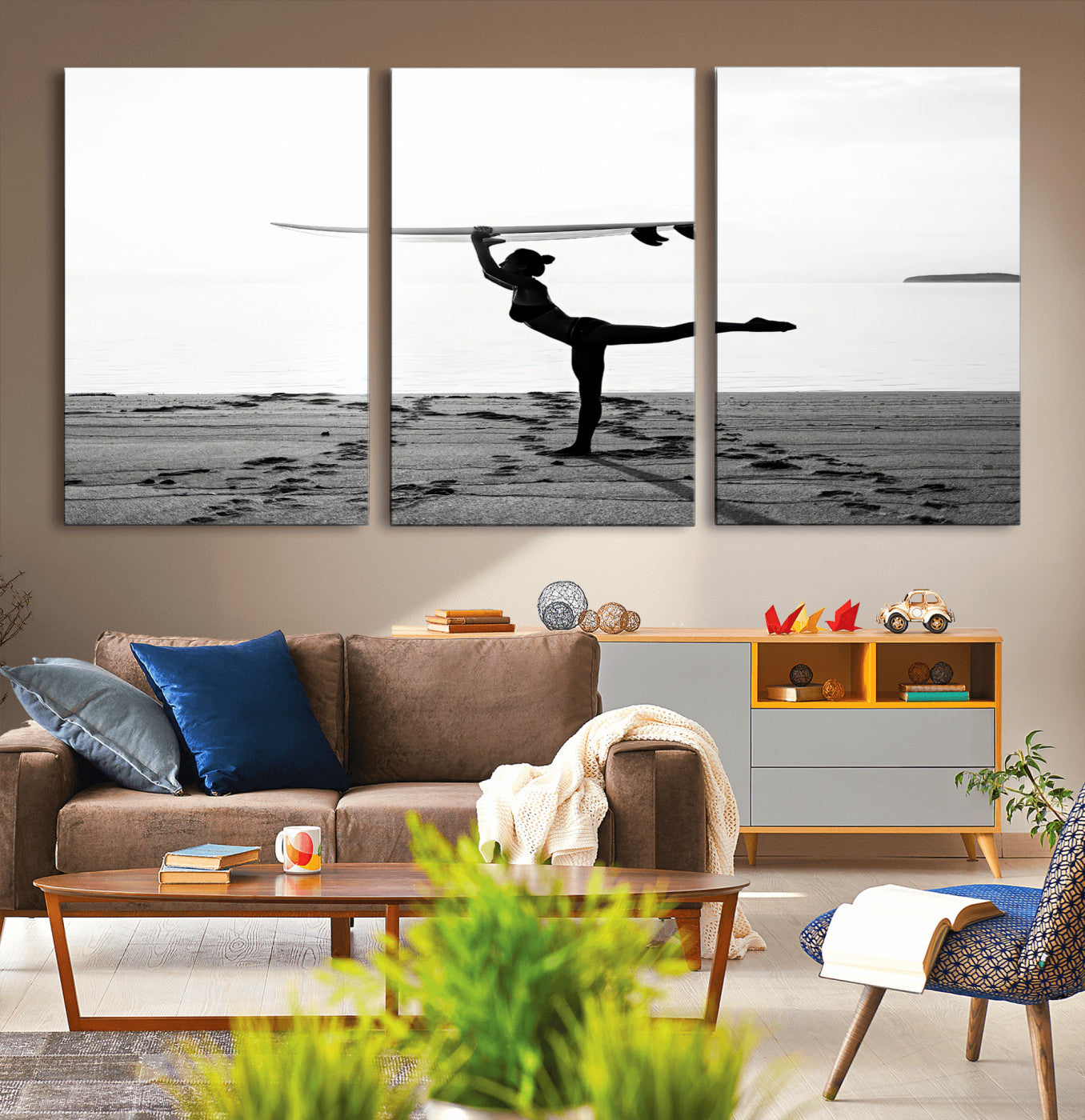 A woman balances a surfboard on her head while striking a yoga pose on the beach, silhouetted against a calm ocean horizon.