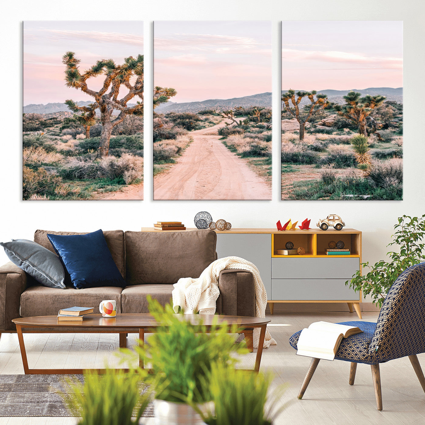 A dusty road winding through Joshua Tree National Park, framed by iconic twisted trees and warm desert tones under a soft pastel sky.