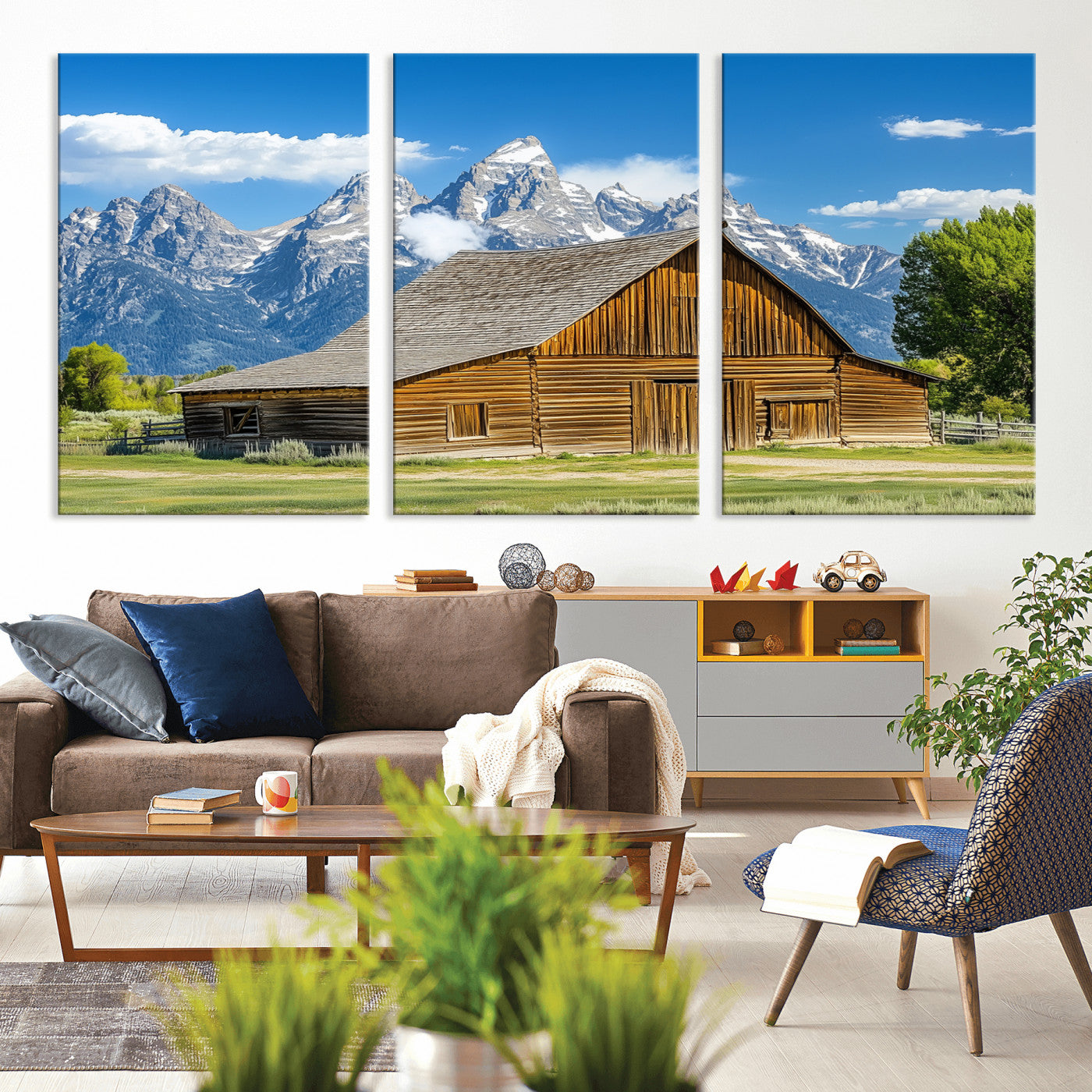 A rustic wooden barn sits in front of towering mountain peaks under a clear blue sky, perfect for farmhouse or cabin style interiors.