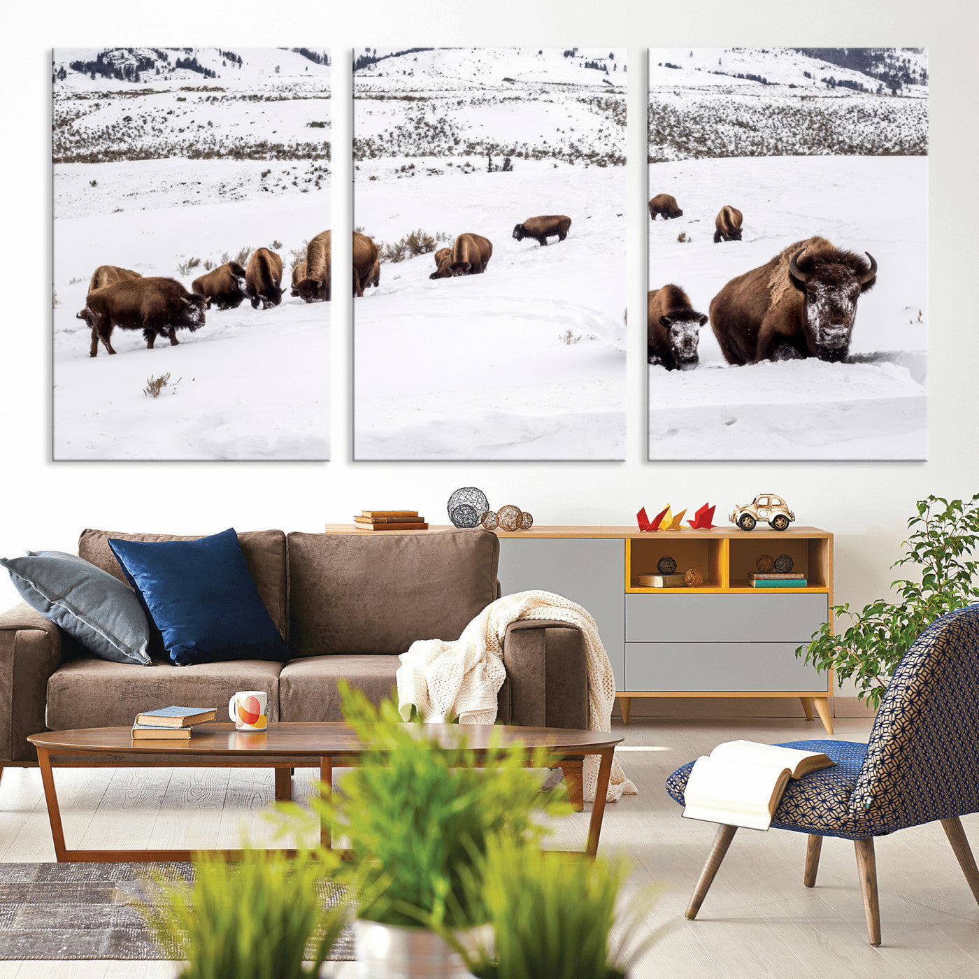 A herd of bison walking through deep snow in a mountain valley, perfect for rustic, cabin or western-themed wall decor.