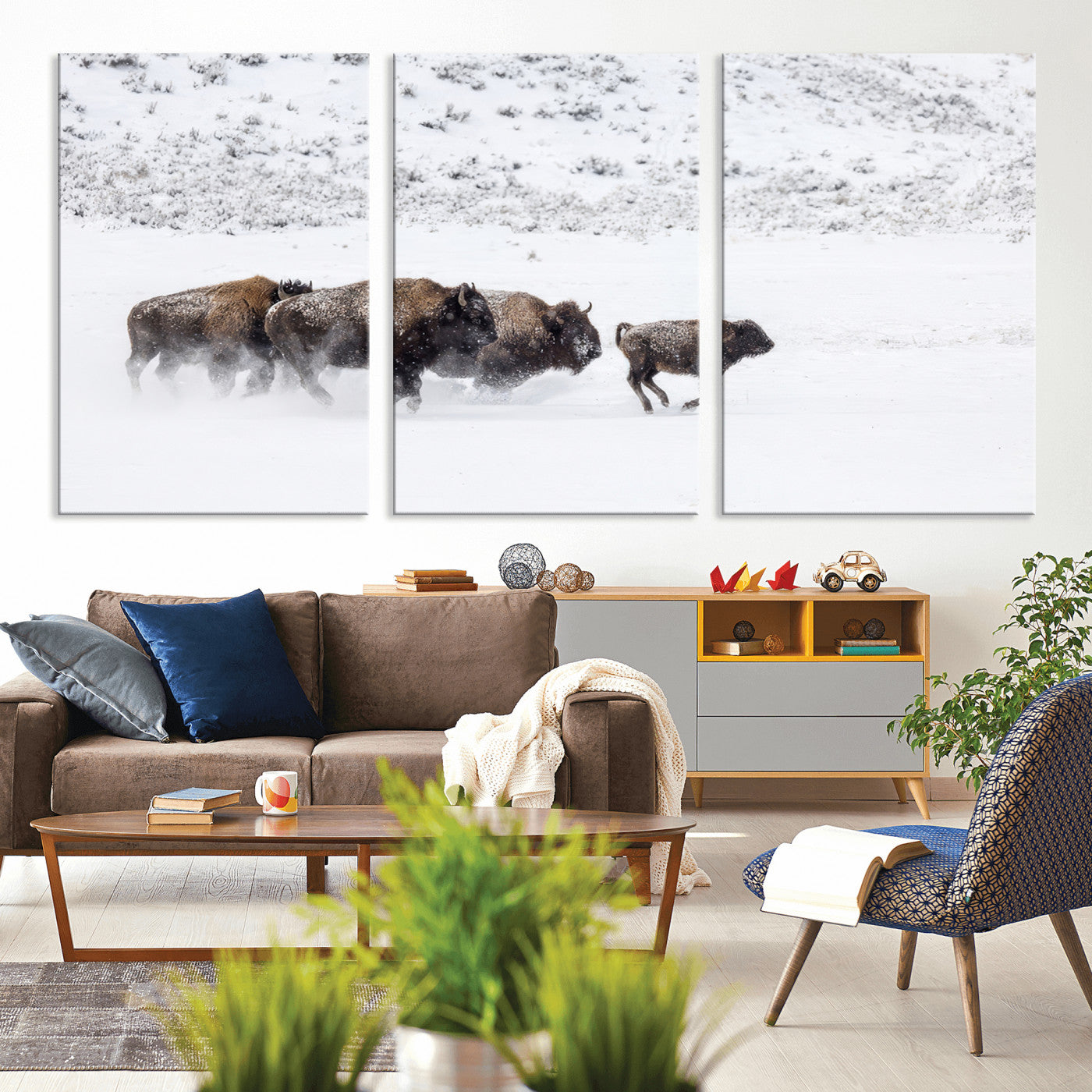 Bison herd running through a snowy open field with mountain backdrop, perfect for rustic or western-themed wall decoration.
