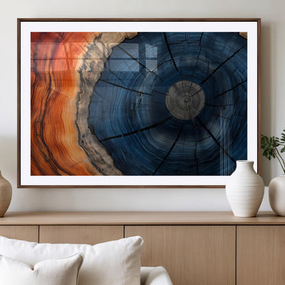 A captivating close-up of a tree trunk, showcasing its concentric rings in rich shades of blue, orange, and brown, highlighting the organic patterns of natural wood.