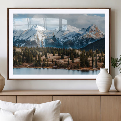 Framed canvas of snowy mountain peaks with pine forest and alpine lake, perfect for winter cabin or wilderness-inspired home decor.