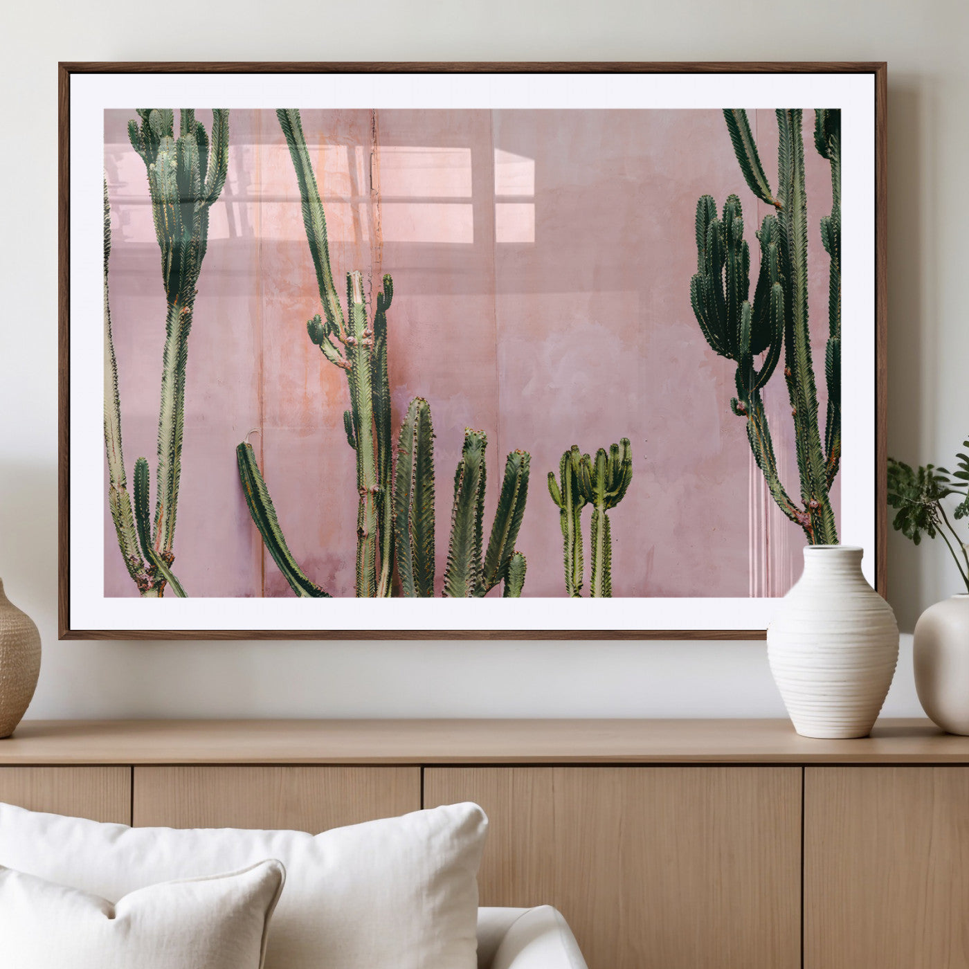 Framed canvas of tall green cacti against a soft pink wall, ideal for modern desert or colorful southwest-inspired home decor.