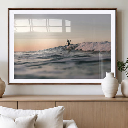 Framed canvas of a female surfer balancing on a wave at sunset, perfect for serene surf or ocean-inspired coastal decor.