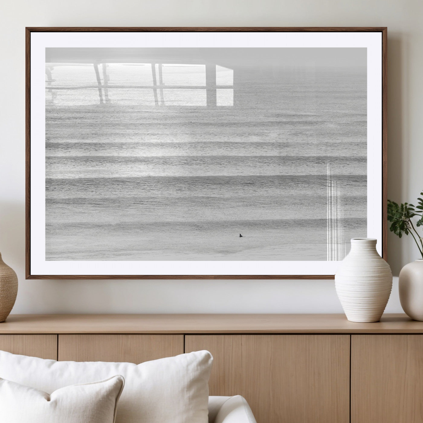 Monochrome photo of a lone surfer in calm layered waves, perfect for minimalist coastal or moody ocean-inspired wall decoration.