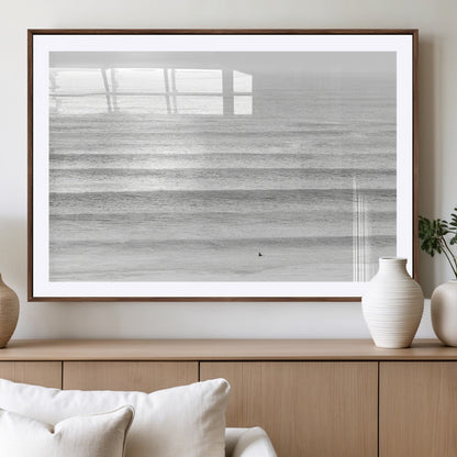 Monochrome photo of a lone surfer in calm layered waves, perfect for minimalist coastal or moody ocean-inspired wall decoration.