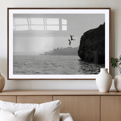 Black and white canvas of two figures cliff jumping into the sea, captured with moody tones, ideal for modern coastal or adventure-themed home decor.   2/2