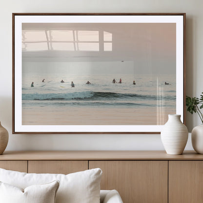 Dreamy photo of surfers waiting on soft pastel waves under a pink sunset sky, ideal for soft coastal minimalist or serene ocean-themed home decor.