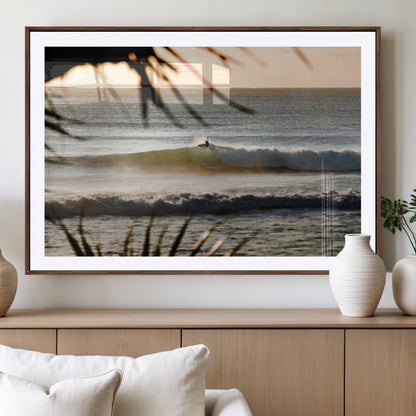 Photo of a surfer riding a golden hour wave at sunset, with tropical tones and dreamy light, perfect for tropical boho or coastal home decor.