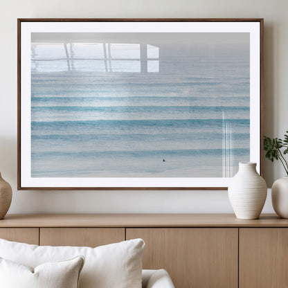 Minimalist ocean view with soft blue waves and a lone surfer, creating a serene and airy coastal aesthetic, perfect for tranquil home decor.