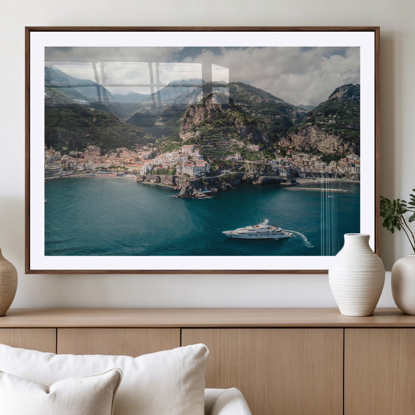 Aerial view of Amalfi Coast, Italy, with colorful hillside houses, lush green mountains, and a luxury yacht sailing in turquoise waters.