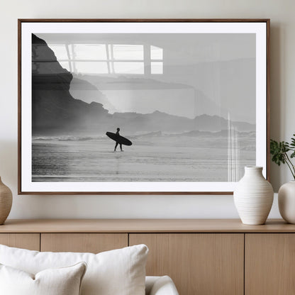 A lone surfer walking along a misty beach with cliffs in the background, carrying their board, capturing a serene and minimal ocean moment.