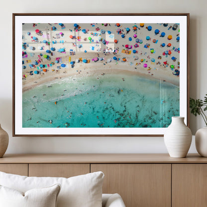 Aerial view of a vibrant beach filled with colorful umbrellas and people enjoying the turquoise ocean, capturing a lively summer vacation scene.