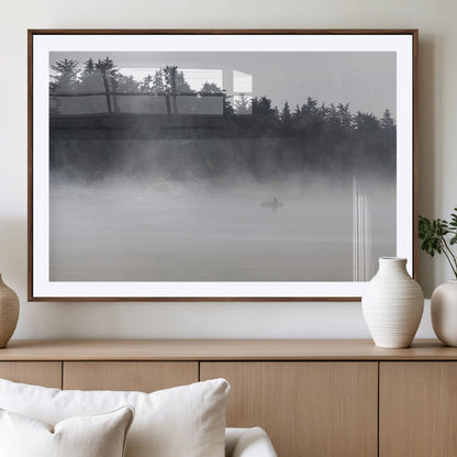 A lone surfer carrying a board through a misty shoreline, surrounded by dense trees and fog, creating a peaceful and mysterious coastal scene.