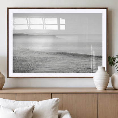 A black and white minimalist seascape featuring soft rolling waves and misty distant cliffs, creating a serene and timeless coastal atmosphere.