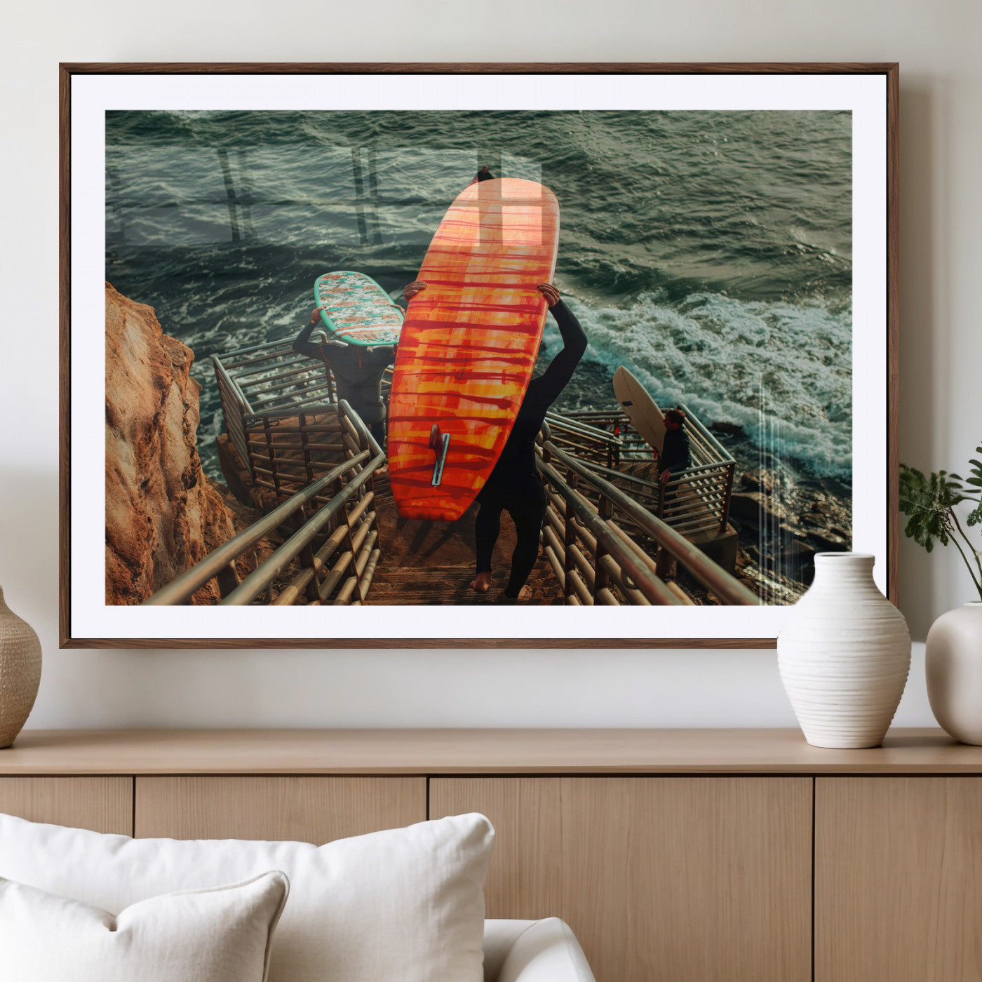 A surfer carrying a bold orange surfboard down a rugged staircase toward the ocean, bathed in golden hour light, capturing the energy of coastal adventure.