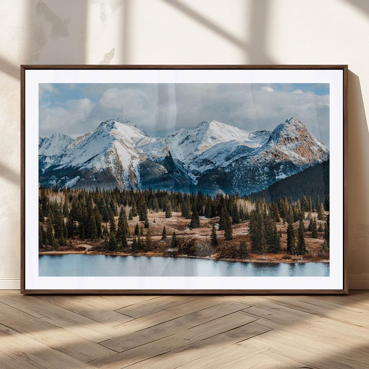 Framed canvas of snowy mountain peaks with pine forest and alpine lake, perfect for winter cabin or wilderness-inspired home decor.