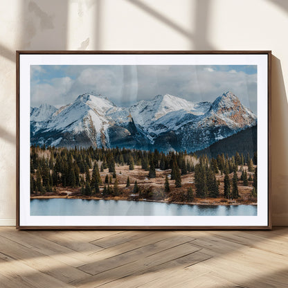 Framed canvas of snowy mountain peaks with pine forest and alpine lake, perfect for winter cabin or wilderness-inspired home decor.