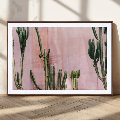 Framed canvas of tall green cacti against a soft pink wall, ideal for modern desert or colorful southwest-inspired home decor.