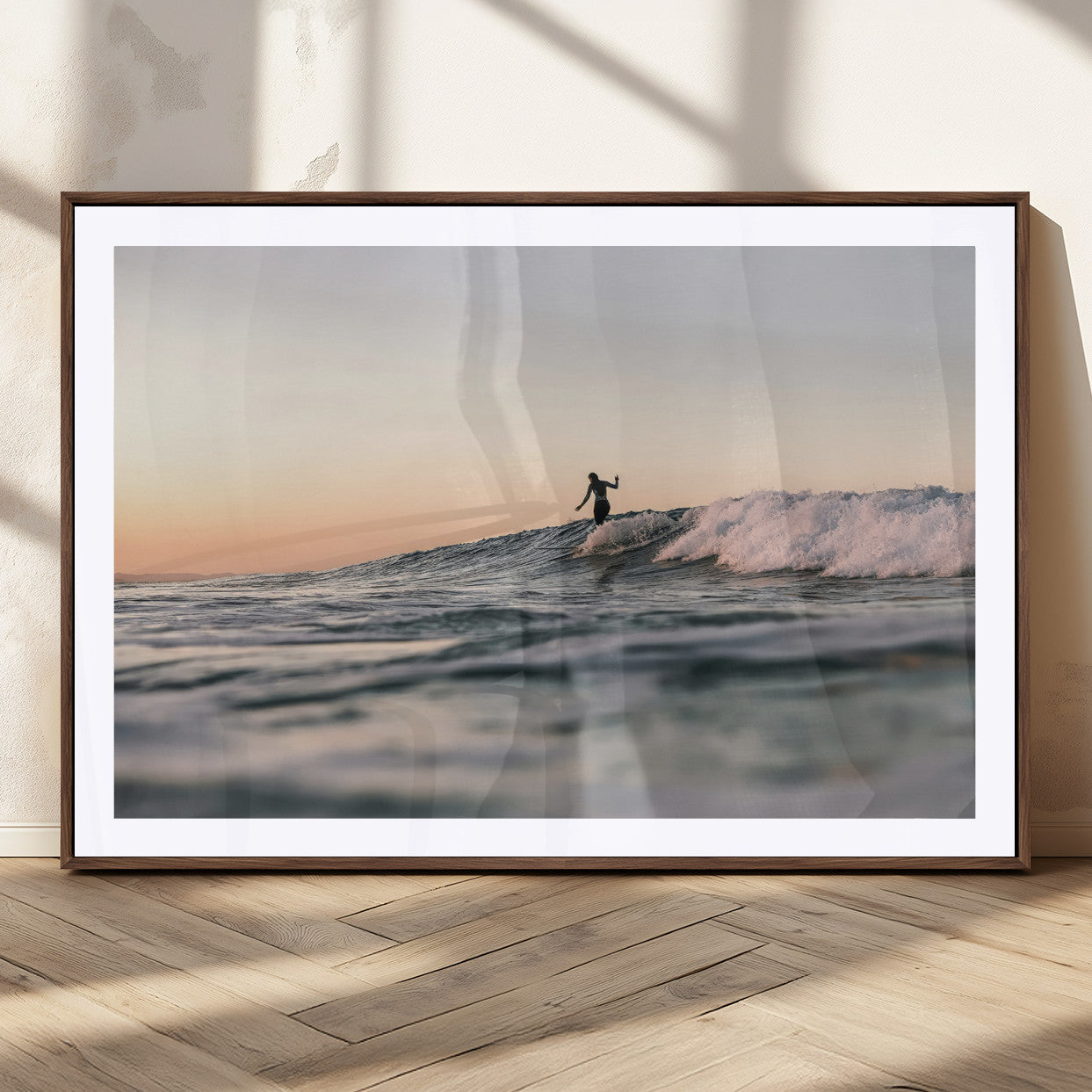 Framed canvas of a female surfer balancing on a wave at sunset, perfect for serene surf or ocean-inspired coastal decor.