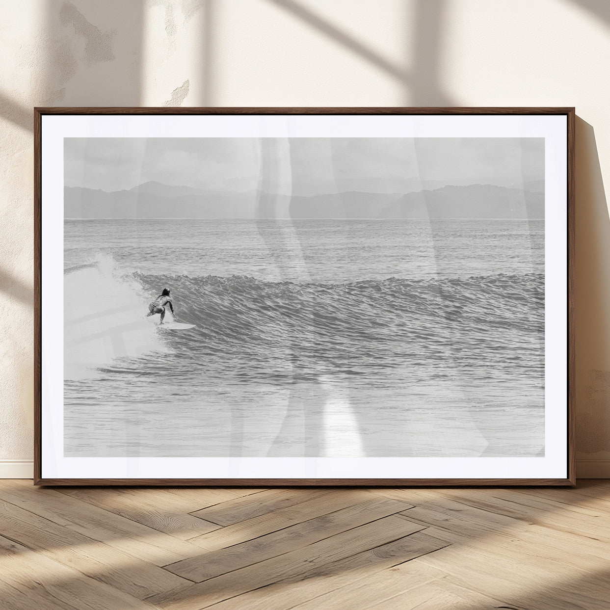 Monochrome photo of a surfer riding a wave with distant mountains, ideal for coastal motion or black and white surf-themed wall decor.