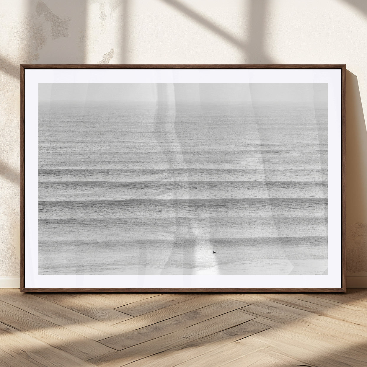 Monochrome photo of a lone surfer in calm layered waves, perfect for minimalist coastal or moody ocean-inspired wall decoration.