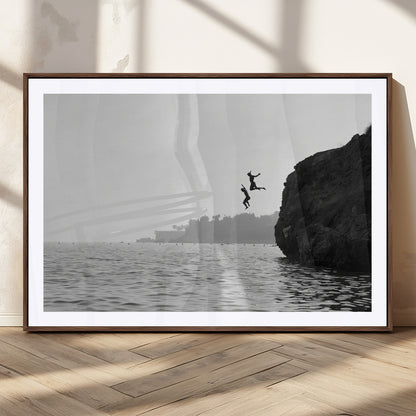 Black and white canvas of two figures cliff jumping into the sea, captured with moody tones, ideal for modern coastal or adventure-themed home decor.   2/2