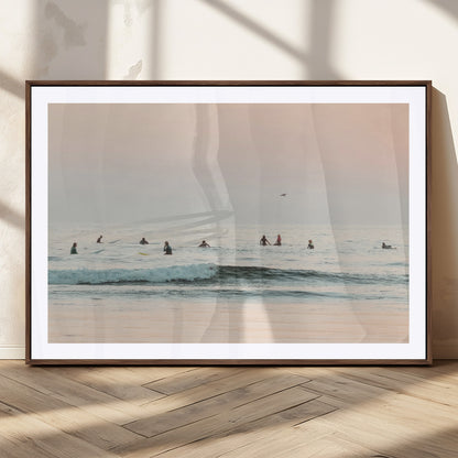 Dreamy photo of surfers waiting on soft pastel waves under a pink sunset sky, ideal for soft coastal minimalist or serene ocean-themed home decor.