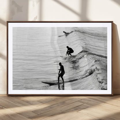 Black and white photo of surfers riding waves in a moody, high-contrast scene, ideal for modern coastal or surf-inspired home decor.