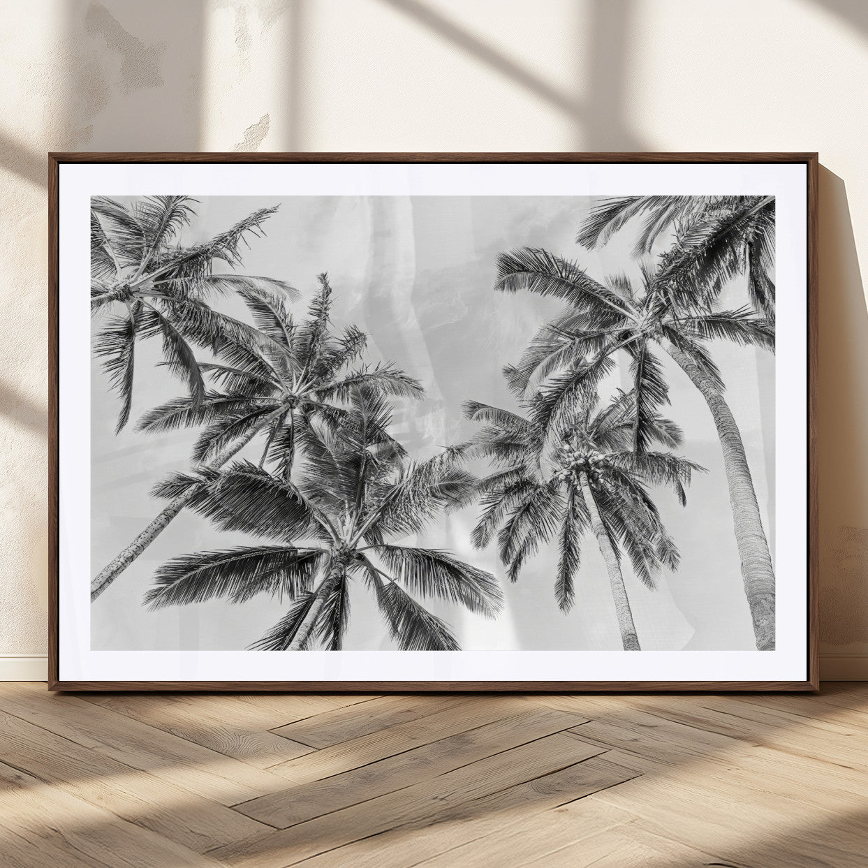 Black and white tropical palm trees viewed from below, swaying gently against a bright sky, creating a serene and elegant coastal atmosphere.