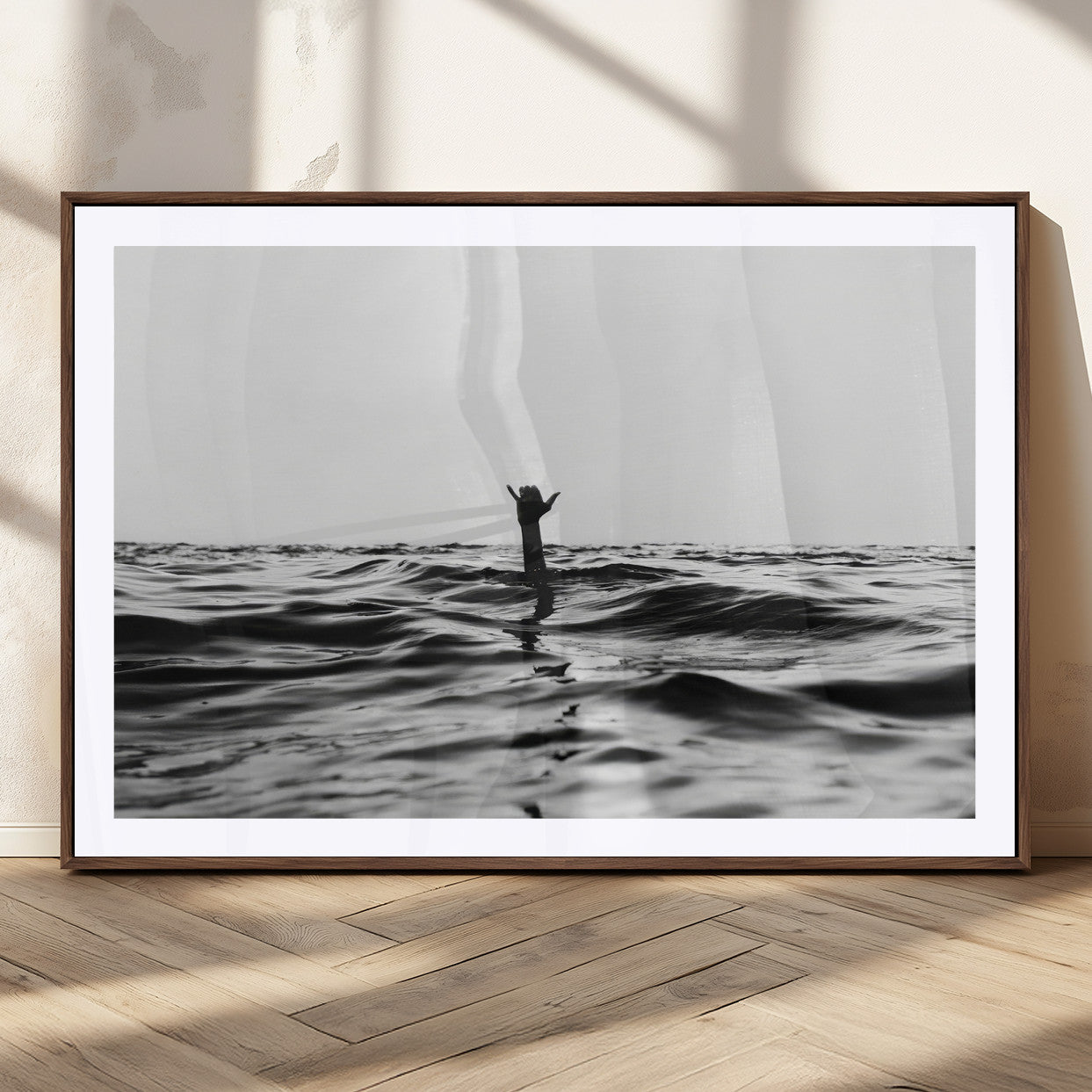 Black and white ocean with a hand making a surfer sign among dark waves, creating a dramatic and minimalist seascape with bold contrast.