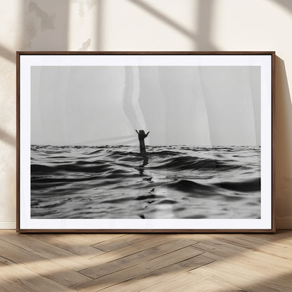 Black and white ocean with a hand making a surfer sign among dark waves, creating a dramatic and minimalist seascape with bold contrast.