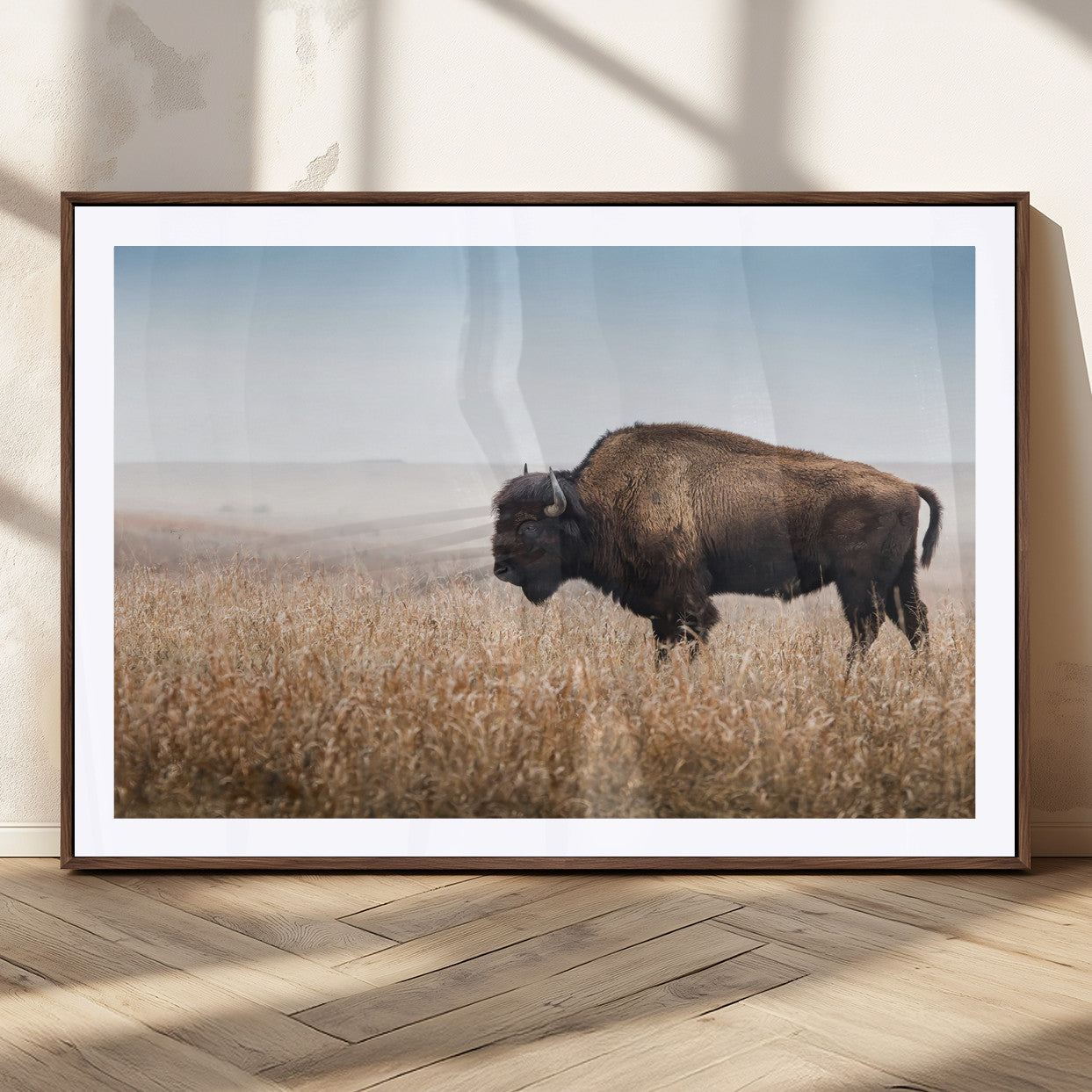 A majestic bison standing in an open prairie field, its strong form blending into the golden grass under a vast blue sky, evoking the wild spirit of the American plains.