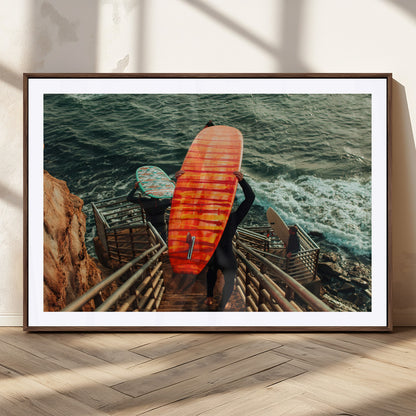 A surfer carrying a bold orange surfboard down a rugged staircase toward the ocean, bathed in golden hour light, capturing the energy of coastal adventure.